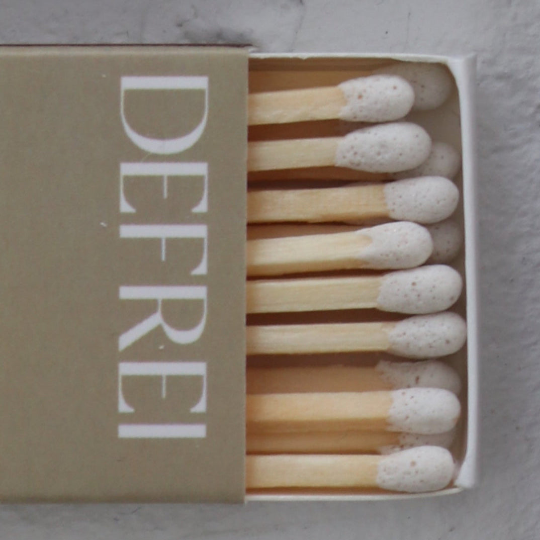 Matchbox with matches and 'DEFREI' branding on a light gray background